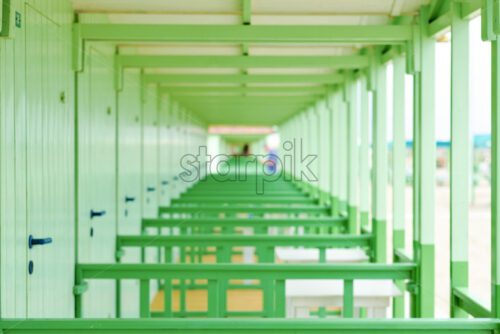 Daylight view to green changing rooms far perspective. Bright sky with clouds and people on background. Forte dei Marmi, Italy - Starpik