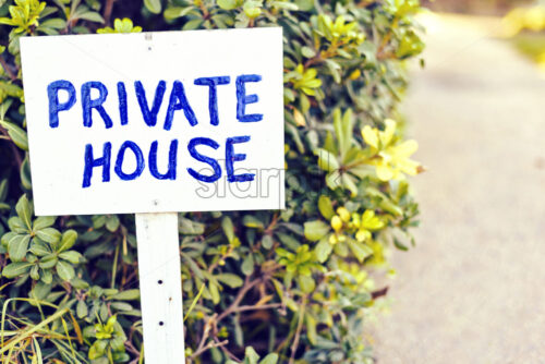 Daylight view to private house wood sign. Green bushes and road on background. Protaras, Cyprus - Starpik