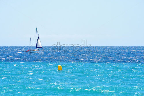 Daylight view to sailing ship cruising on water. Yellow buoys on background. Bright blue clear sky. Place for text, negative copy space. Cannes, France - Starpik