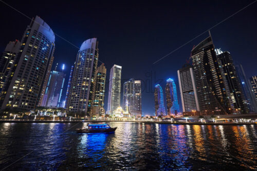 Dubai Marina at night with colorful touristic boats cruising on water. United Arab Emirates - Starpik