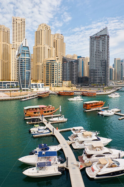 Dubai marina cityscape at daylight. Clear sky. United Arab Emirates. Yachts parked in port. - Starpik