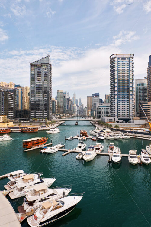 Dubai marina cityscape at daylight. Clear sky. United Arab Emirates. Yachts parked in port. - Starpik