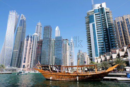 Dubai marina cityscape at daylight. Wooden boat on foreground. Clear sky. United Arab Emirates - Starpik