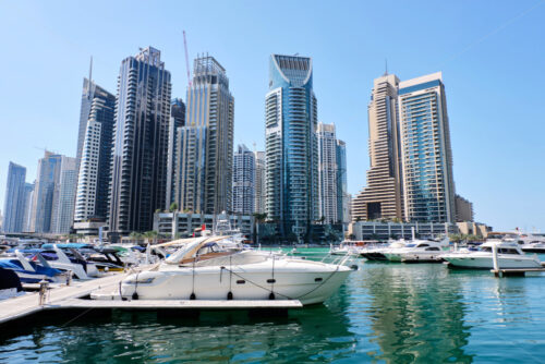 Dubai marina cityscape at daylight. Yachts parked in port on foreground. Clear sky. United Arab Emirates - Starpik