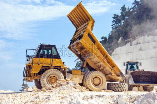 Dump truck working with excavator in Marble Quarry. Thassos, Greece - Starpik