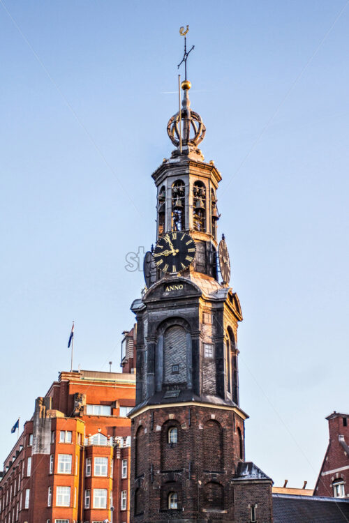 Famous Mint Tower at sunset from bottom. Bright blue sky with clouds on background. Amsterdam, Netherlands - Starpik