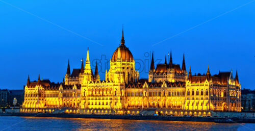 Famous parliament at night blue hour. Warm yellow lights glowing on building. Danube river with reflections. Negative copy space, place for text. Budapest, Hungary - Starpik