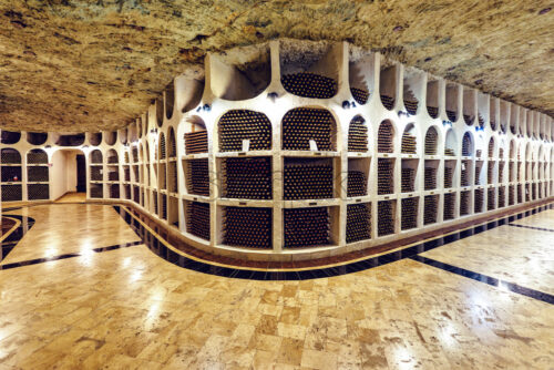 Famous wine cellars in wide perspective. Bright lights illuminating interior. Old stone ceiling. Cricova, Moldova - Starpik