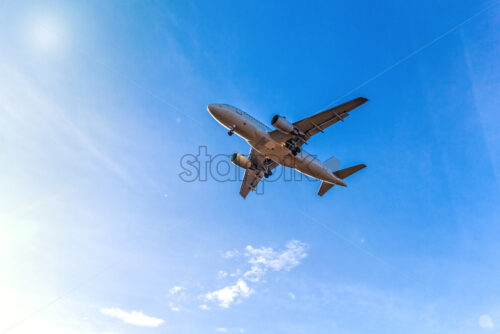 Flying aircraft with passengers over blue sky into the shining sunlight landscape - Starpik