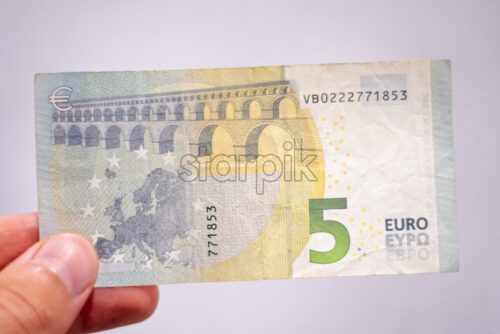 Hand holding a five euro banknote. Blured and isolated close up shot - Starpik