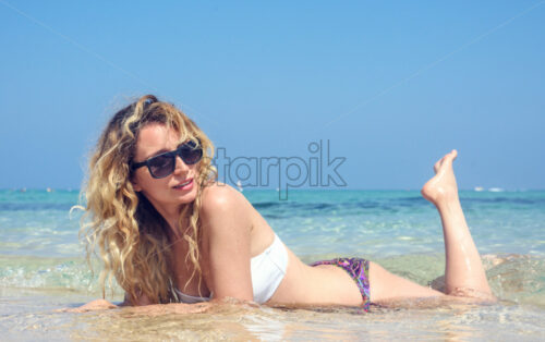 Happy Woman laying at the beach in Cyprus. Beautiful Summer seaside views. Enjoy sunny days beauty - Starpik