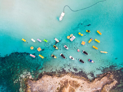 Island with boats parked near fig tree bay beach. Aerial vertical drone shot. Protaras, Cyprus - Starpik