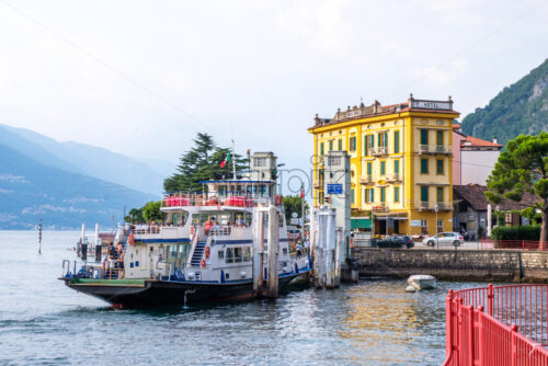 LOMBARDY, ITALY – AUGUST 03, 2018: Ferry loading in Varenna town at sunset. Hotel Olivedo on background - Starpik