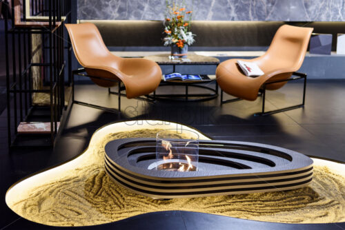 Loft interior with burning fireplace, sand and brown chairs - Starpik