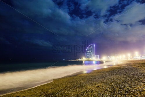 Long exposure Barcelona beach coastline at night. Futuristic hotel on background. Spain - Starpik