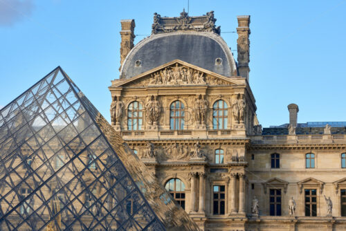 Louvre Museum facade at sunset. Pyramid on foreground. Paris, France - Starpik