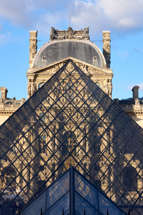 Louvre Museum facade at sunset. View through pyramid glass. Paris, France - Starpik