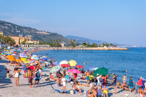 MENTON, FRANCE – AUGUST 06, 2018: Beach with people having fun. Blue sky on background - Starpik