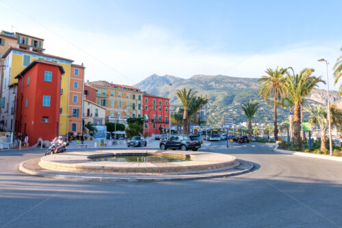 MENTON, FRANCE – AUGUST 06, 2018: City at sunset with cars riding on road. Colorful buildings and mountains - Starpik