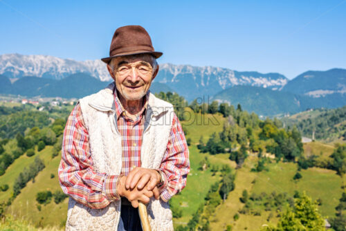 MOIECIU, ROMANIA – AUGUST 31, 2017: Daylight view to old Shepherd on beautiful picturesque landscape background with mountains. Negative copy space, place for text. Bright blue clear sky - Starpik