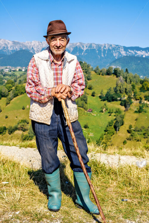 MOIECIU, ROMANIA – AUGUST 31, 2017: Daylight view to old Shepherd on beautiful picturesque landscape background with mountains. Negative copy space, place for text. Bright blue clear sky - Starpik