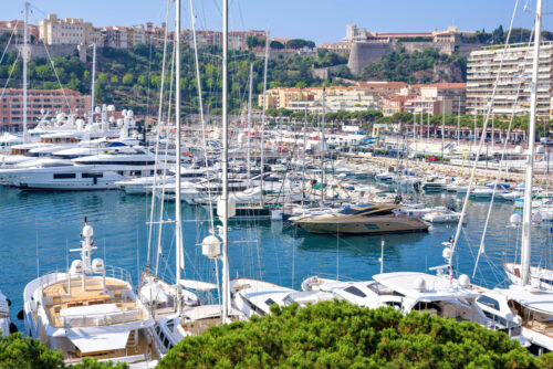 MONACO, FRANCE – JUNE 28, 2017: Daylight sunny view to parked luxury yachts and tall buildings constructed in city. Bright blue clear sky. - Starpik