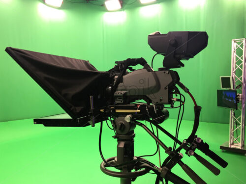 Modern empty green video recording and broadcasting studio with tv channel led screen and metalic stands, text prompter, lights on - Starpik