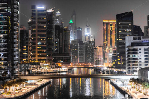 Modern looking view in Dubai at night, United Arab Emirates. Bright lights with orange predominance on the building - Starpik