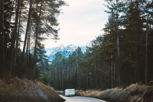 Mystical road in the forest with camper car riding on it. Mountains on background. Innsbruck, Austria - Starpik