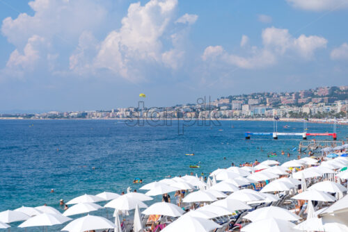 NICE, FRANCE – AUGUST 08, 2018: Beach at daylight. Man parasailing. Clouds on background. View from top - Starpik