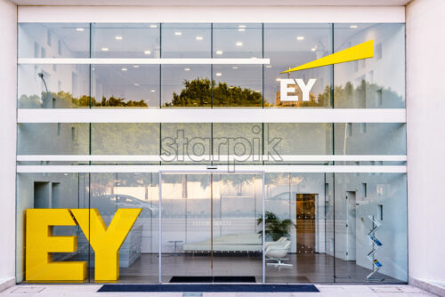 NICOSIA, CYPRUS – SEPTEMBER 14, 2017: Daylight view to EY company Office. Road and lights reflecting in windows - Starpik