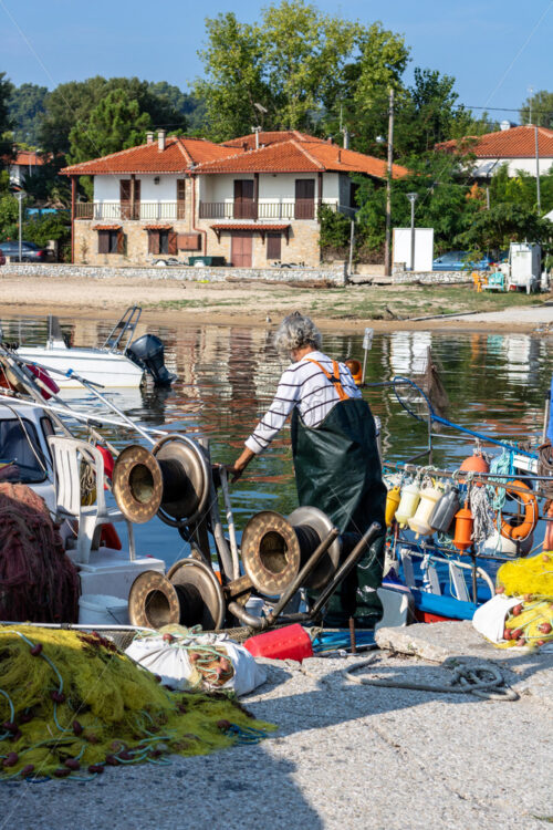 Old fisherman works in a port from Halkidiki, Greece. Fishing equipment on the ground - Starpik