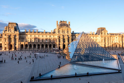 PARIS, FRANCE – OCTOBER 03, 2018: Bright and warm sunlight hitting Louvre museum. Blue accents in the shadows and on the pyramid - Starpik