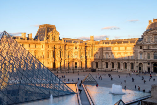 PARIS, FRANCE – OCTOBER 03, 2018: Bright and warm sunlight hitting Louvre museum. Blue accents in the shadows and on the pyramid - Starpik