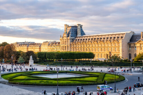 PARIS, FRANCE – OCTOBER 03, 2018: Close up shot to Louvre a part of Louvre from the side. Lots of tourists on the road. Bright and warm sunlight hitting the bulding - Starpik