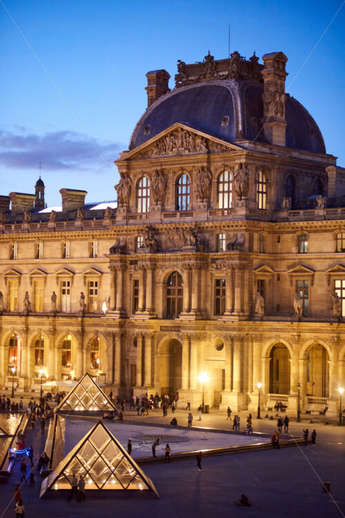 PARIS, FRANCE – OCTOBER 03, 2018: Louvre Museum facade at blue hour. People on foreground - Starpik