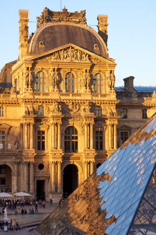 PARIS, FRANCE – OCTOBER 03, 2018: Louvre Museum facade at sunset. People and pyramid on foreground - Starpik