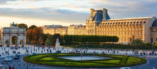 PARIS, FRANCE – OCTOBER 03, 2018: Tuileries Garden and Louvre Museum at sunset. People on promenade. Yellow sunshine reflecting on building - Starpik