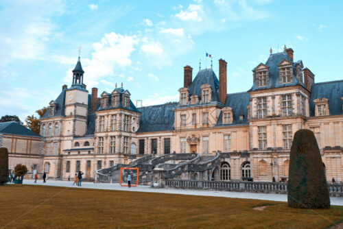 PARIS, FRANCE – SEPTEMBER 09, 2018: The Palace of Fontainebleau at daylight. People walking in front. Orange and teal colors - Starpik