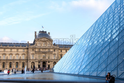 PARIS, FRANCE – SEPTEMBER 28, 2018: Louvre museum during at sunset. Reflections on the blue and transparent pyramid - Starpik