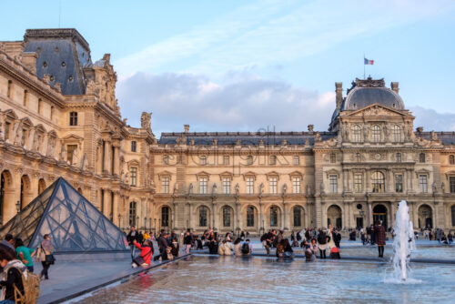 PARIS, FRANCE – SEPTEMBER 28, 2018: Louvre museum during at sunset. Reflections on the blue and transparent pyramid - Starpik