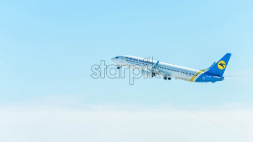 PRAGUE, CZECH REPUBLIC – MARCH 23, 2018: Ukraine International Boeing 737-800 taking off from Boryspil airport. Landing gear retracting. Blue isolated background with blurred clouds. - Starpik