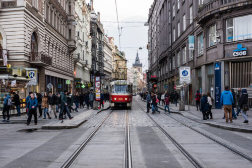 PRAGUE, CZECH REPUBLIC – MARCH 24, 2018: Streets of the city in a cloudy and rainy day. Tramway riding on tracks and people exploring local landmarks. Hotels and baroque buildings on background. - Starpik