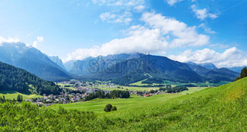 Panorama of Toblach city at daylight. Green grass and vibrant blue sky. - Starpik