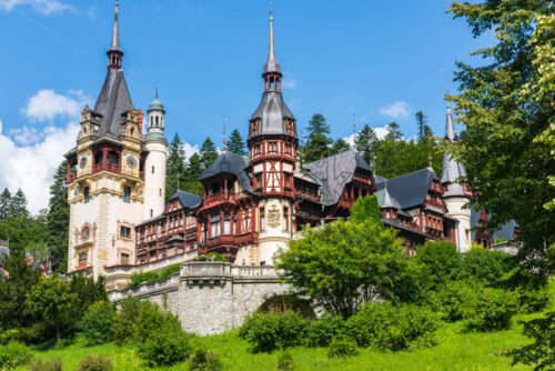 Peles Castle in sunlight in Brasov. Bottom view. Blue sky with white clouds - Starpik