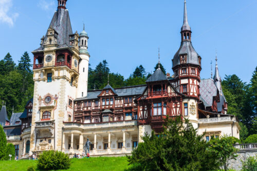 Peles Castle in sunlight in Brasov. Bottom view. Blue sky with white clouds - Starpik