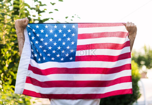 Photo of a man holding with both hands the american flag, for memorial day of 4th of july - Starpik