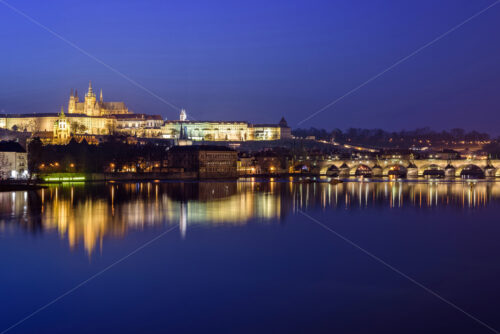 Prague Castle and Charles Bridge at night blue hour with lights glowing and reflecting on water. Negative copy space, place for text. Czech Republic - Starpik