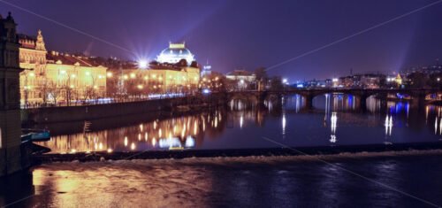 Prague city with warm lights glowing on streets and reflecting on water and ground in a rainy day. Legion Bridge on background. Negative copy space, place for text. Czech Republic - Starpik