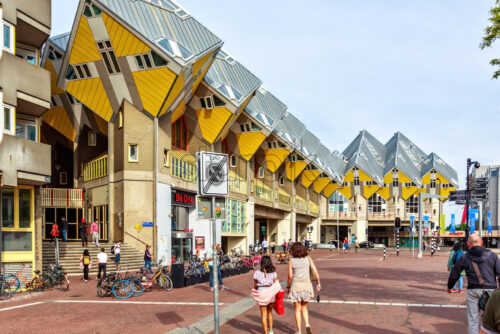 ROTTERDAM, NETHERLANDS – MAY 12, 2018: Famous cube houses in a sunny day. Bright blue sky on background. People walking and exploring local landmarks. Parked bicycles - Starpik